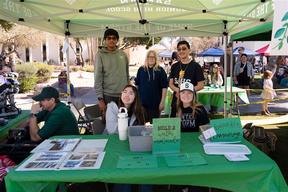 An image of students from Santan Junior High School smiling by their booth which encourages guests to build a water molecule.